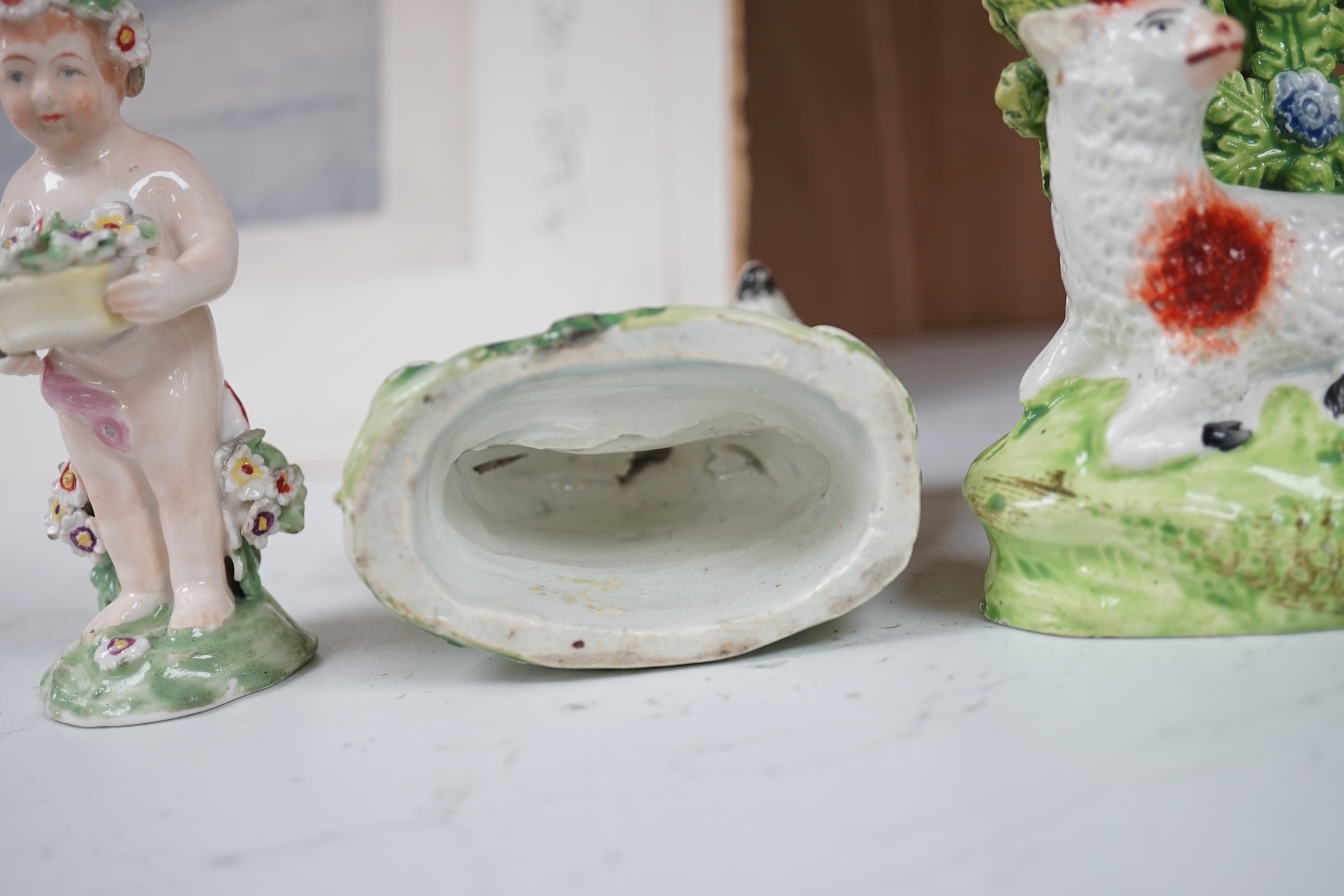 A pair of early 19th century pearlware models of sheep, an English porcelain ‘sheep’ ring tree and a Derby figure of a cherub, tallest 10 cm. Condition - ring tree restored the others fair to good